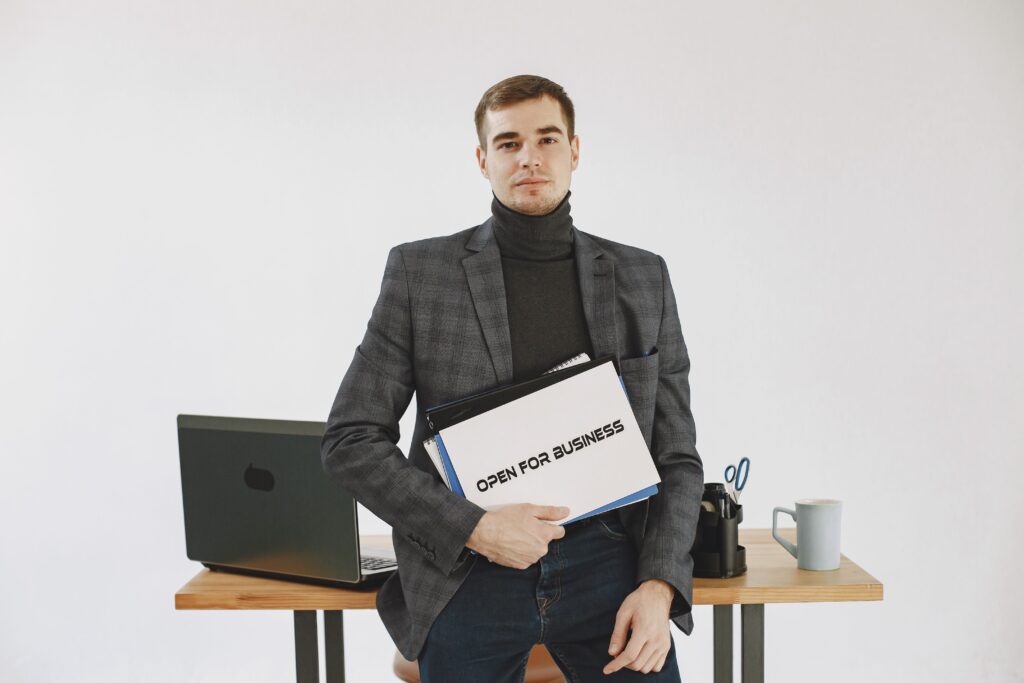 Businessman holding an open for business sign when learning how to start a business