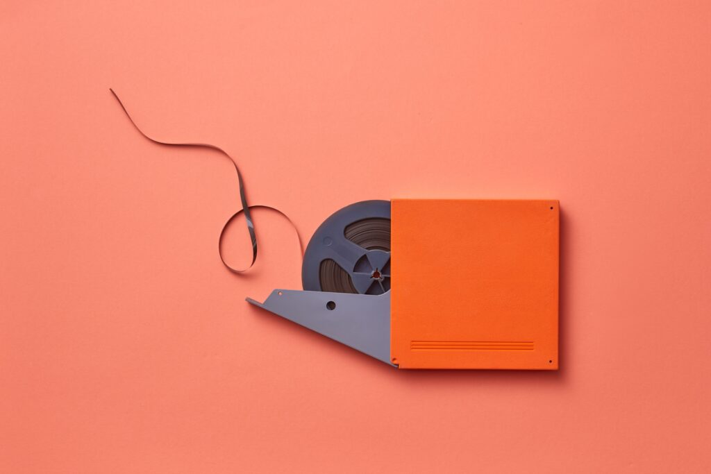 Close-up of a vintage film reel on an orange background, symbolizing the classic films behind Rob Reiner net worth