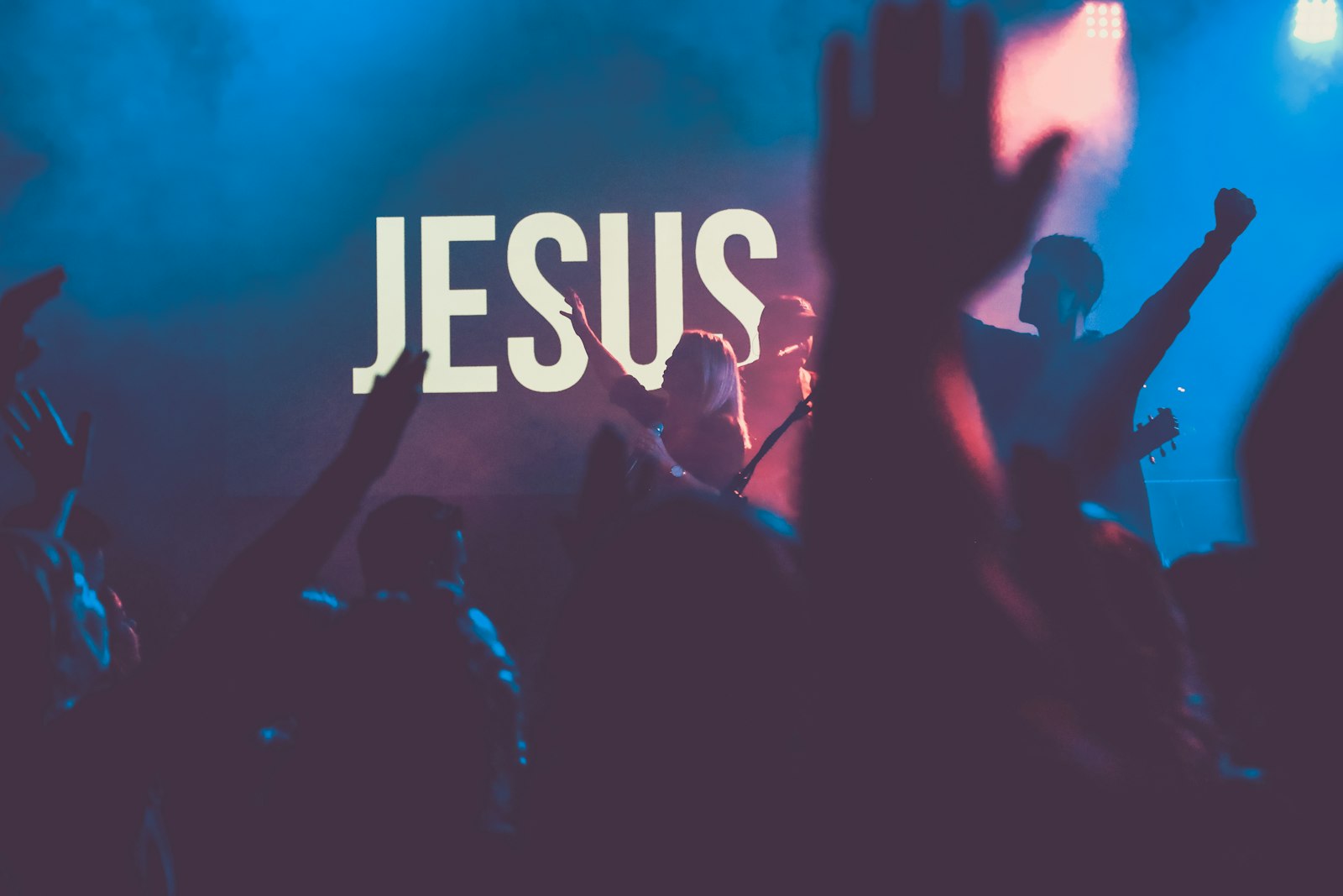 Worship concert crowd with raised hands - why churches still sing Alpha and Omega
